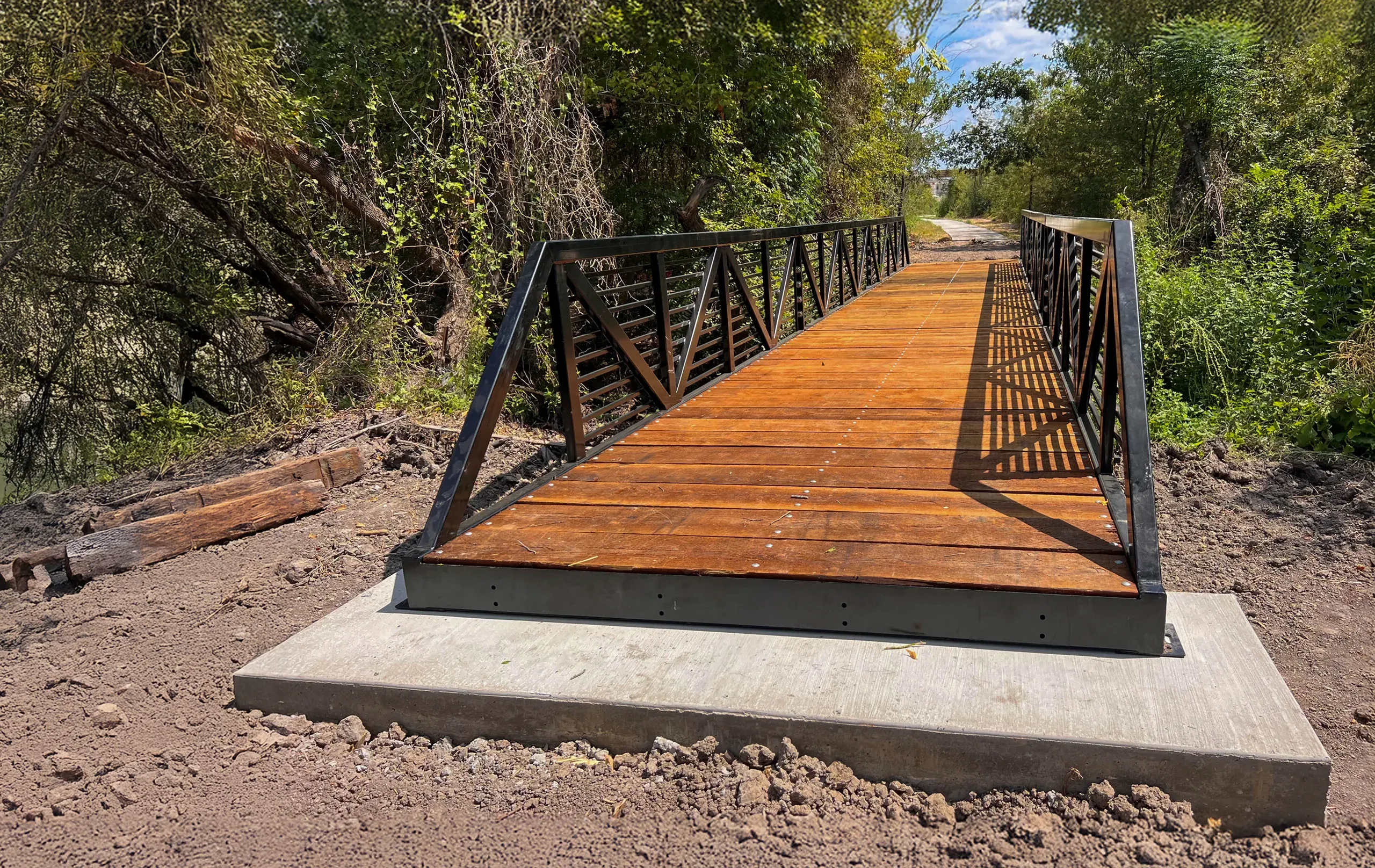 Modular steel-and-timber trail bridge on concrete pads.