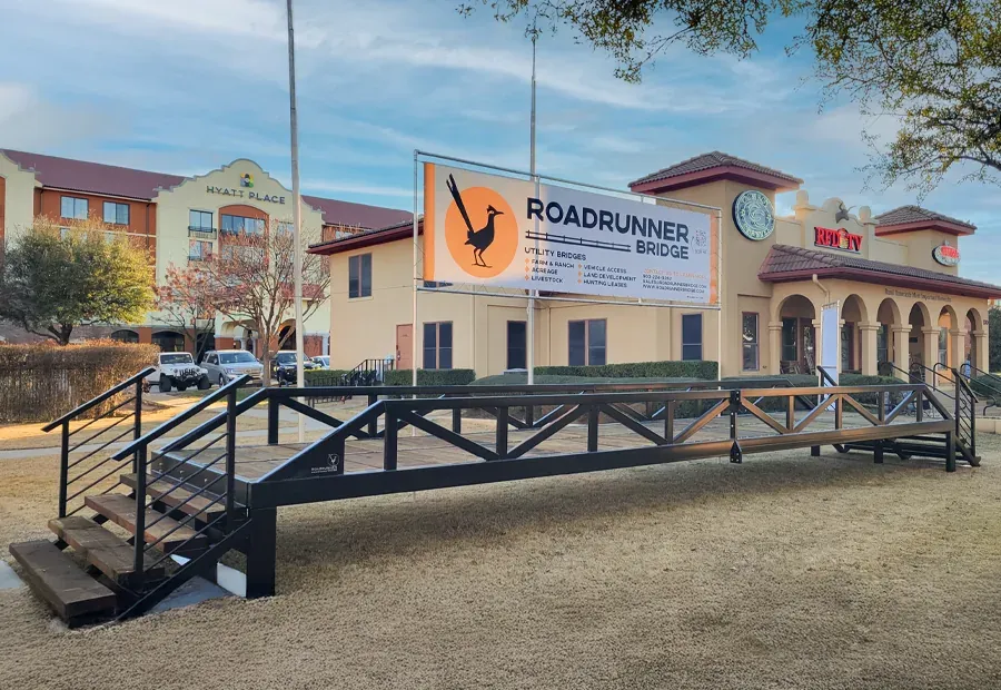 Prefabricated steel-and-timber utility bridge demo with black truss rails and stair access.